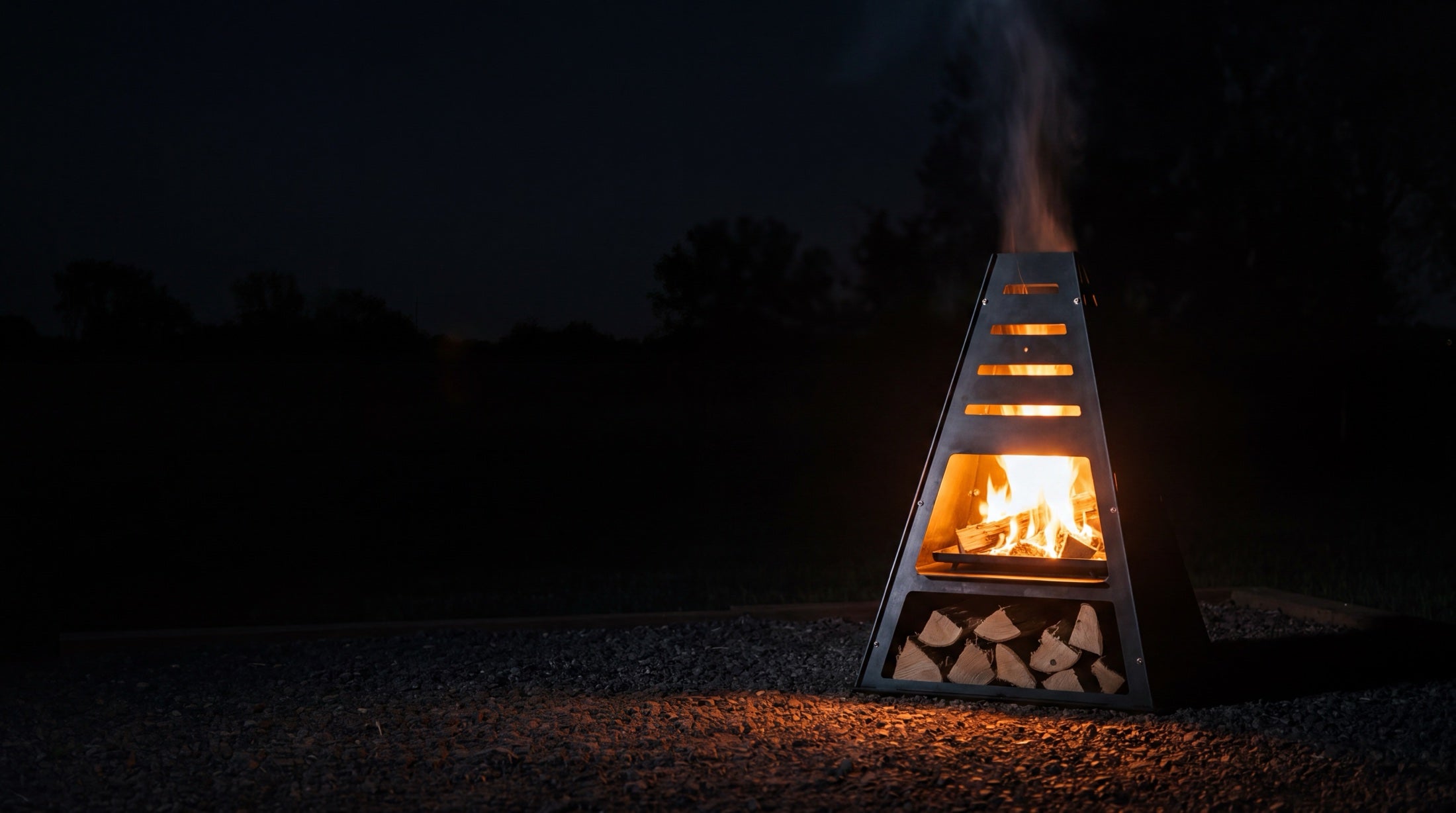 Pyro Tower metal chiminea burning at night, dramatic close view