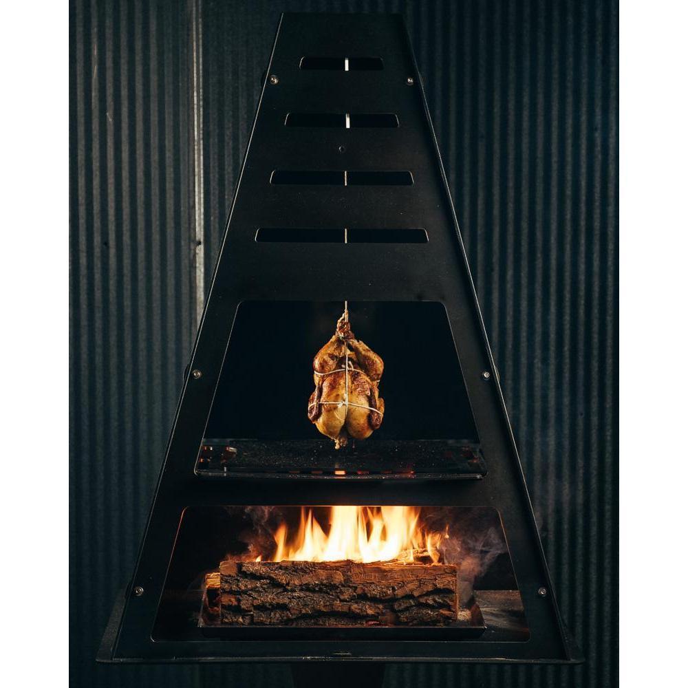 Roasted chicken hanging from Pyro Tower cooking over wood fire